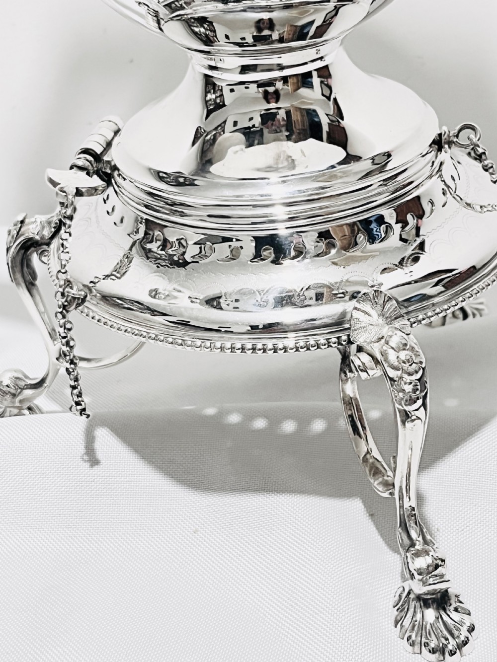 An ornate late Victorian silver-plated tea kettle with engraved geometric panels resting on a matching spirit burner stand. View V