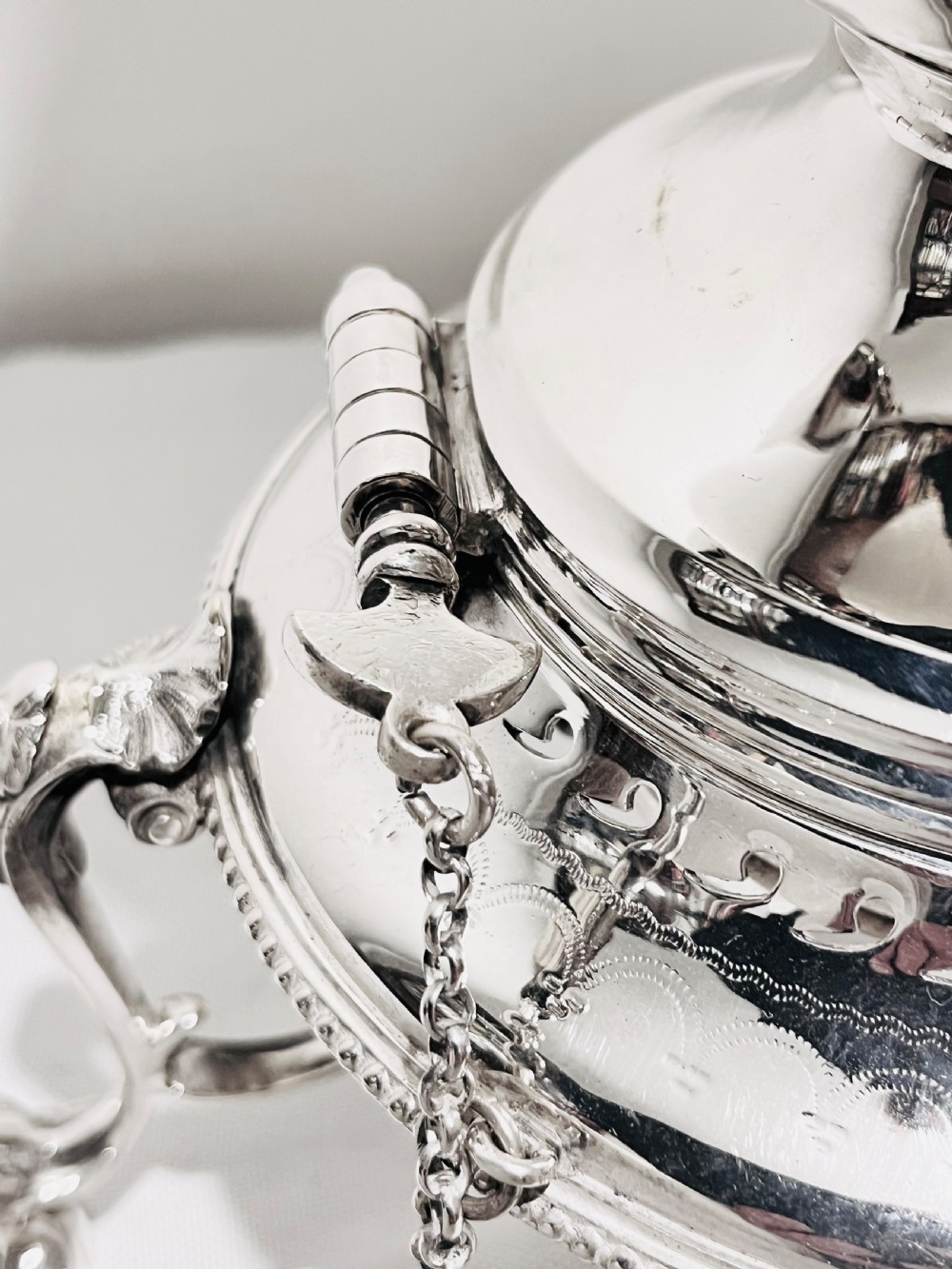 An ornate late Victorian silver-plated tea kettle with engraved geometric panels resting on a matching spirit burner stand. View VIII
