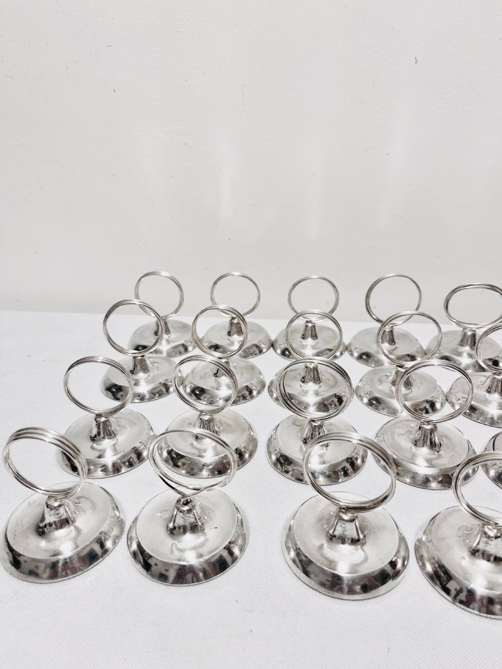 A collection of twenty-four silver-plated menu holders featuring domed bases and circular clip rings. View II