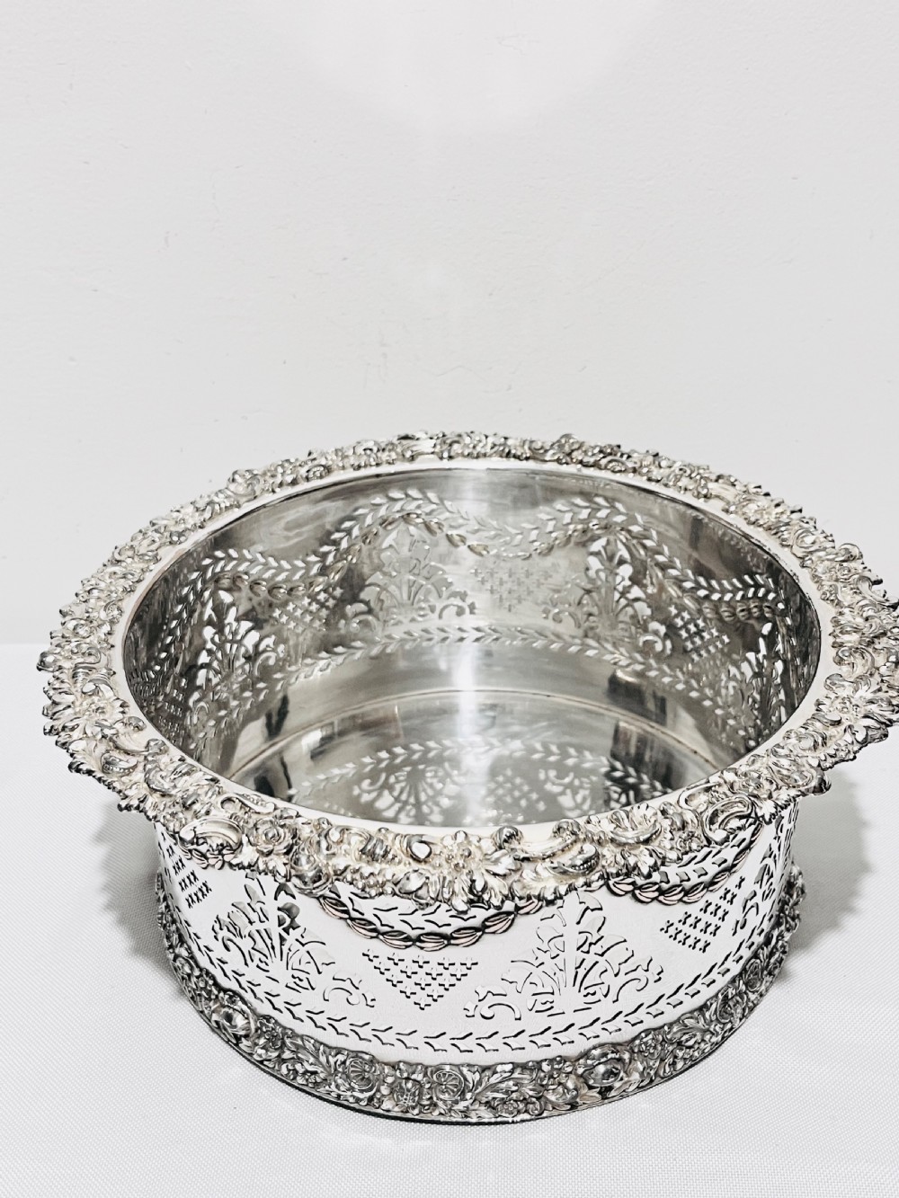 A large cylindrical antique silver-plated coaster featuring pierced reticulated fretwork, garland swags, and embossed floral borders. View III