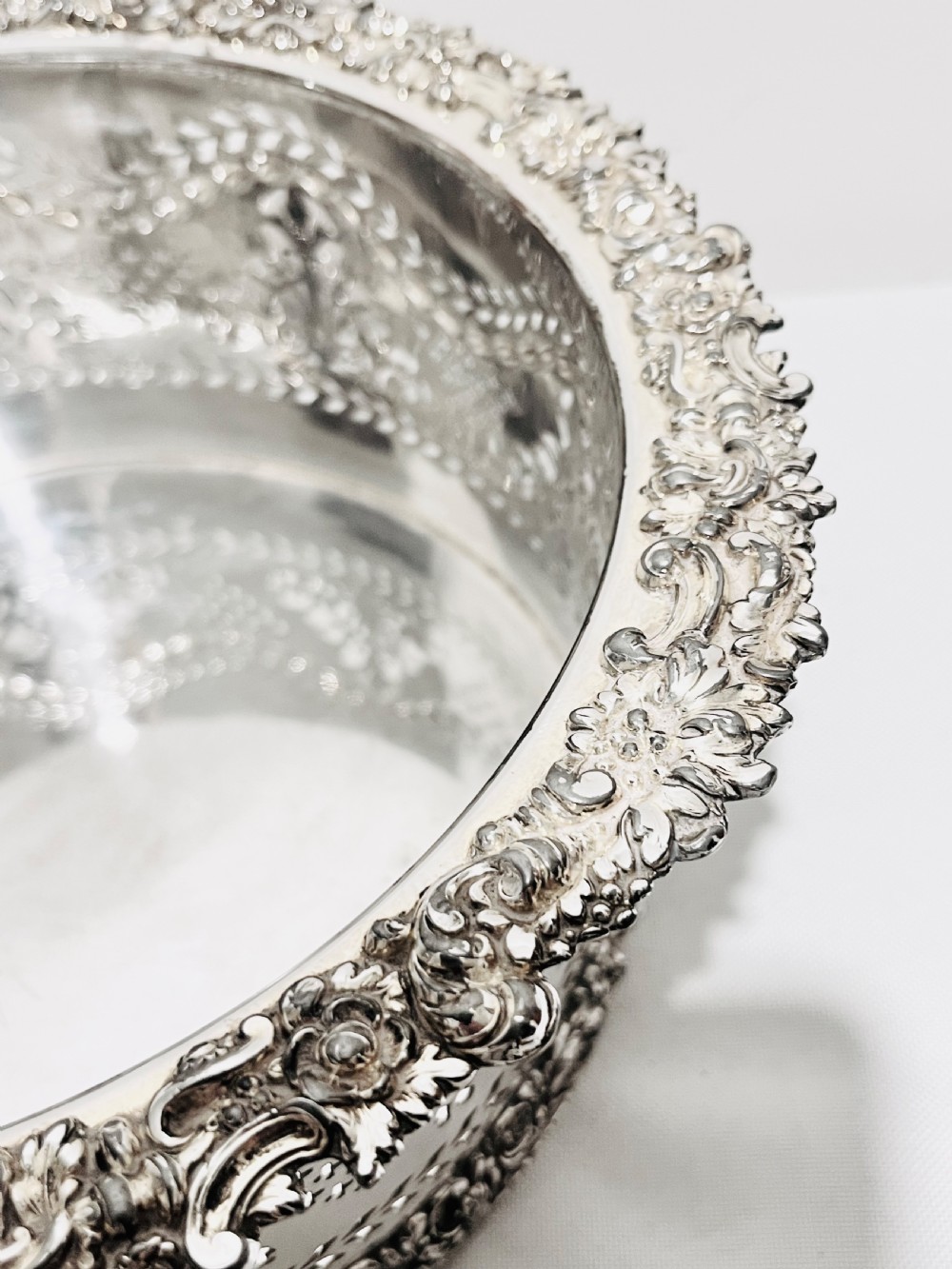 A large cylindrical antique silver-plated coaster featuring pierced reticulated fretwork, garland swags, and embossed floral borders. View V