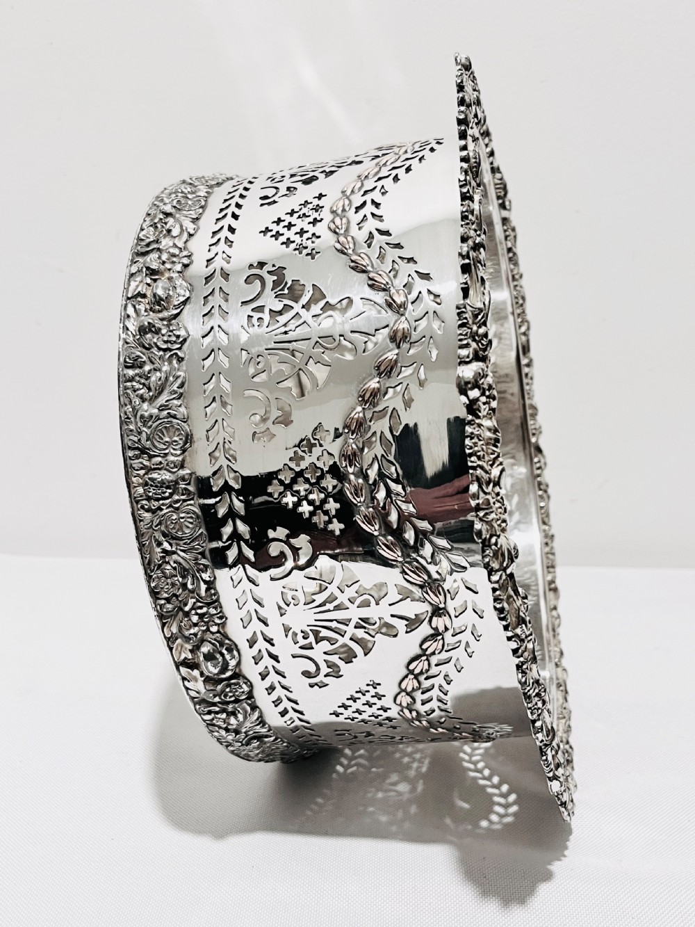 A large cylindrical antique silver-plated coaster featuring pierced reticulated fretwork, garland swags, and embossed floral borders. View VI