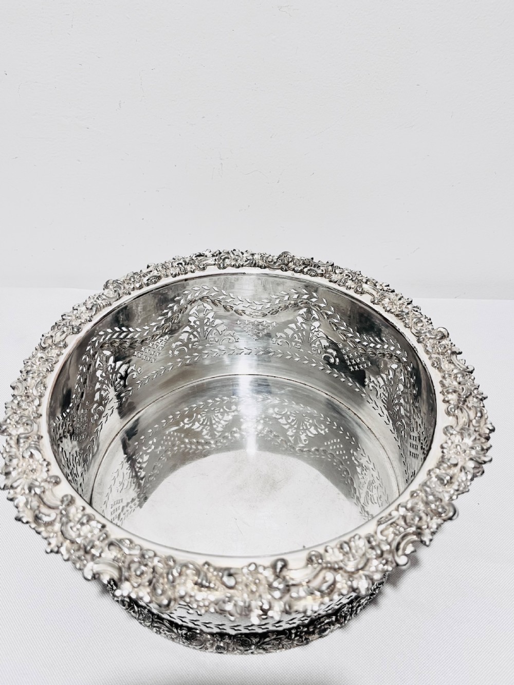A large cylindrical antique silver-plated coaster featuring pierced reticulated fretwork, garland swags, and embossed floral borders. View VII
