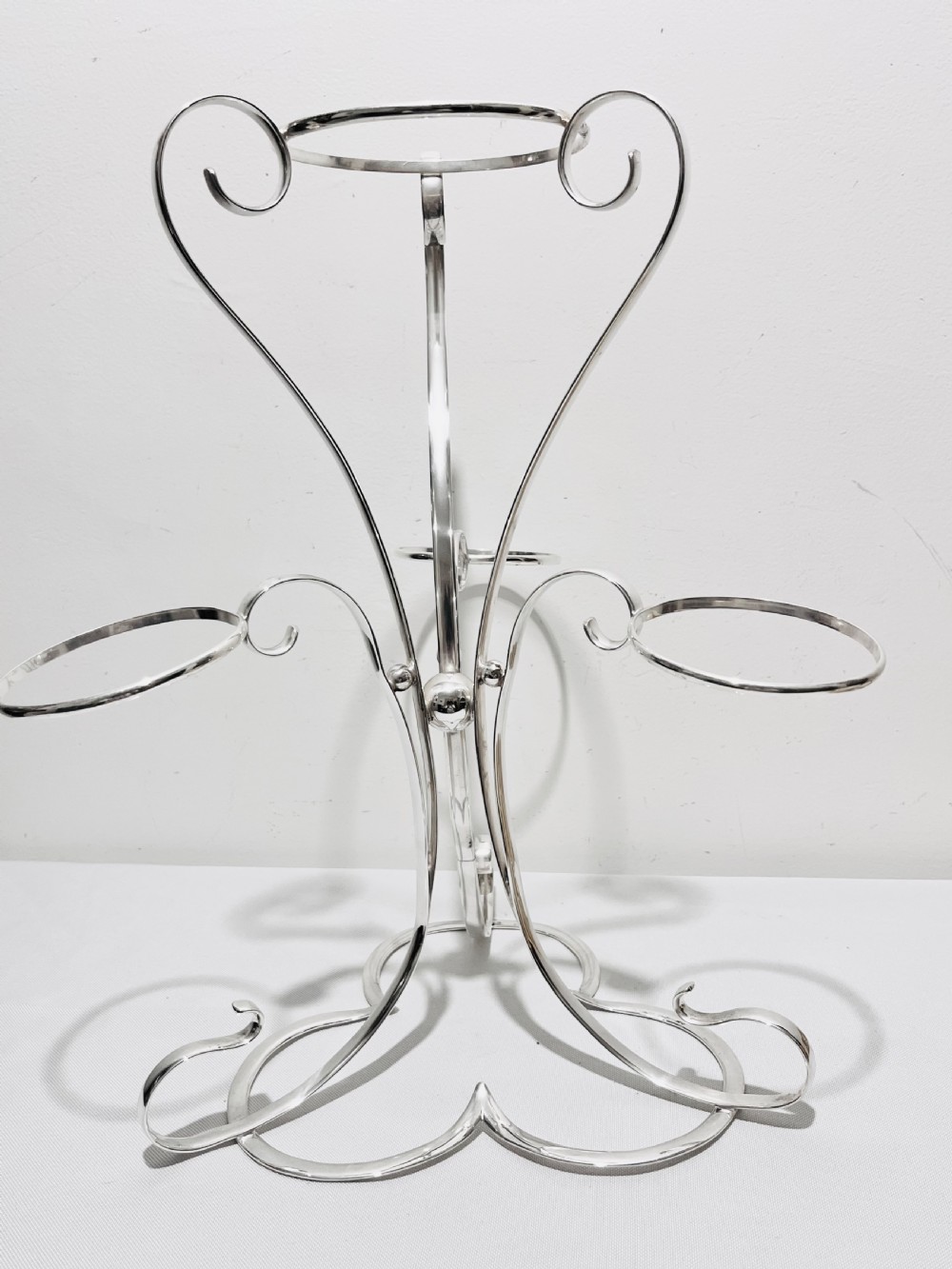 An Edwardian silver-plated tiered stand holding four cream basketweave ceramic pots on scrolling wirework supports. View II