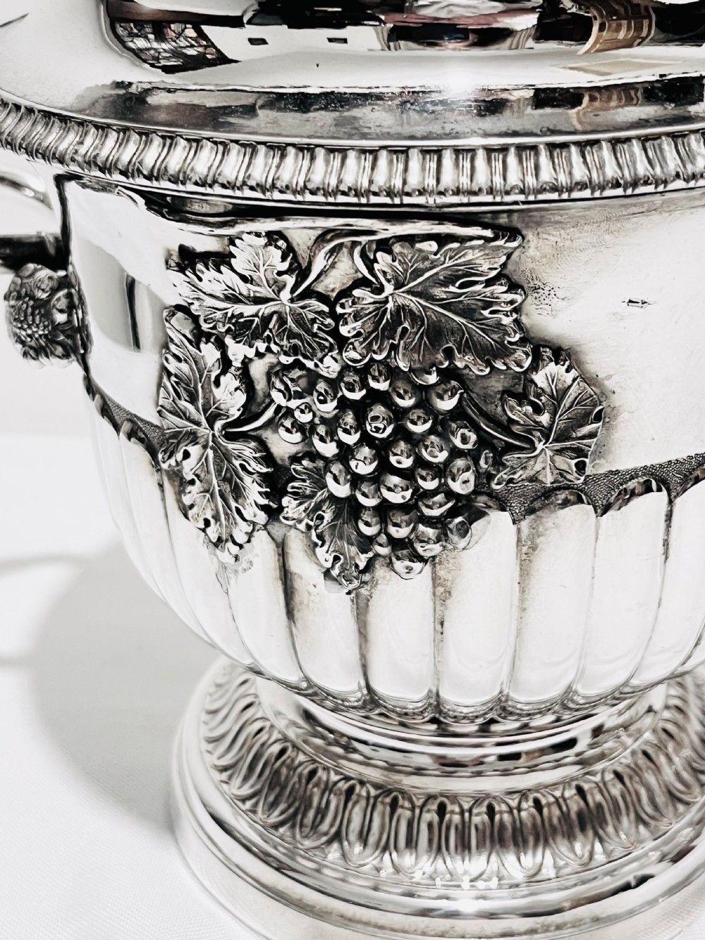 A pair of Regency silver-plated urn-shaped wine coolers featuring raised grapevine motifs, gadrooned rims, fluted bases, and twin side handles. View II