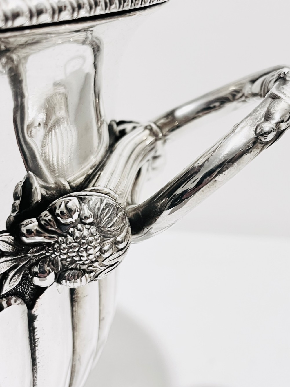 A pair of Regency silver-plated urn-shaped wine coolers featuring raised grapevine motifs, gadrooned rims, fluted bases, and twin side handles. View V