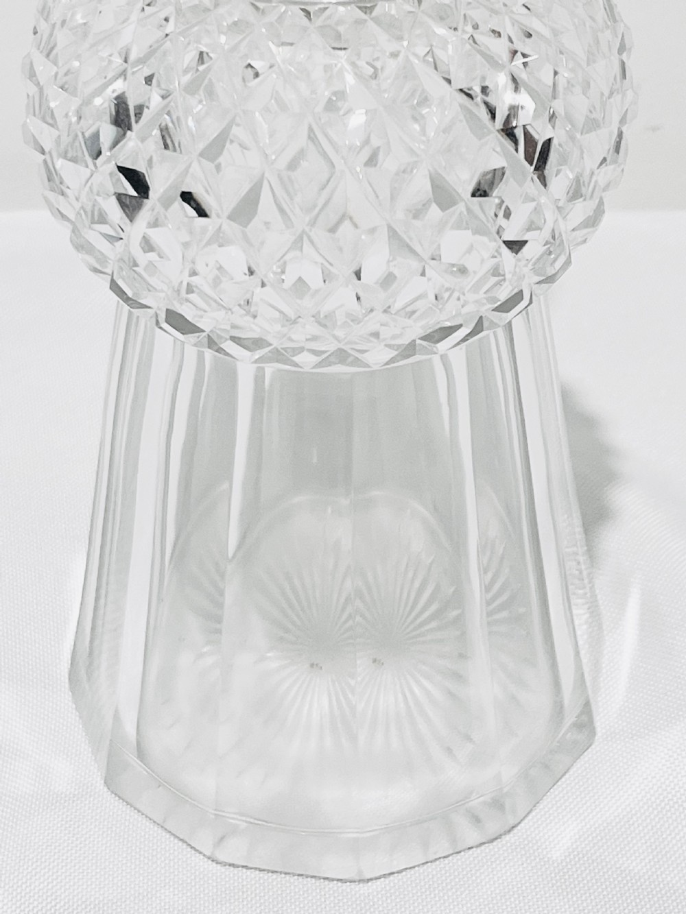 A clear cut glass spirit decanter shaped like a Scottish thistle with a fluted silver-plated metal collar and a faceted spherical glass stopper. View II