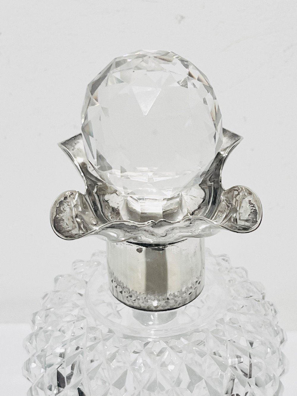 A clear cut glass spirit decanter shaped like a Scottish thistle with a fluted silver-plated metal collar and a faceted spherical glass stopper. View III