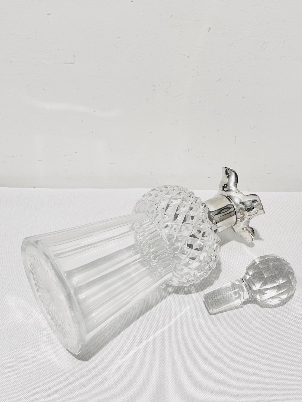 A clear cut glass spirit decanter shaped like a Scottish thistle with a fluted silver-plated metal collar and a faceted spherical glass stopper. View VI