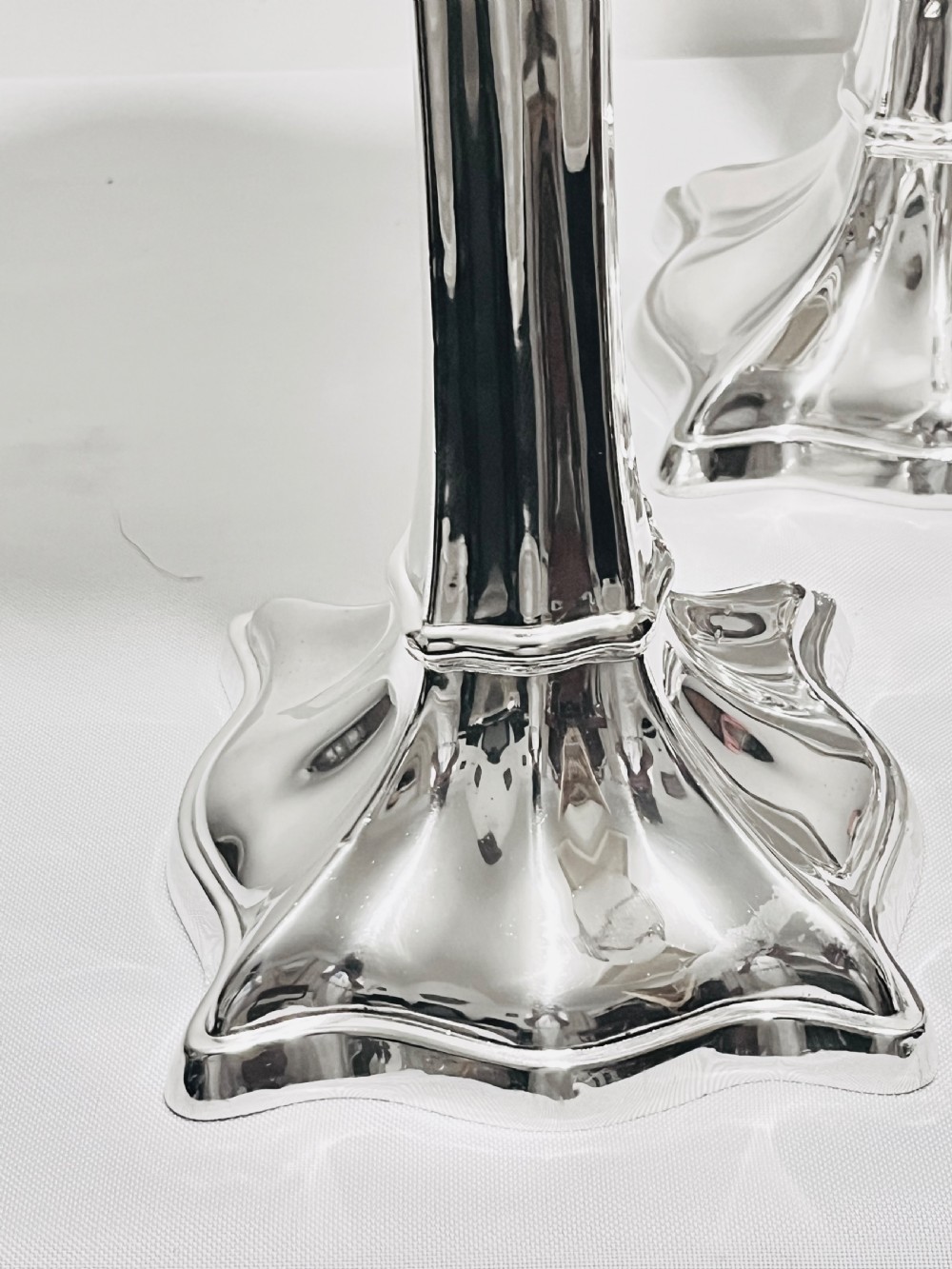 A set of four tall polished silver-plated trumpet vases featuring fluted stems, scalloped rims, and flared stepped bases. View II
