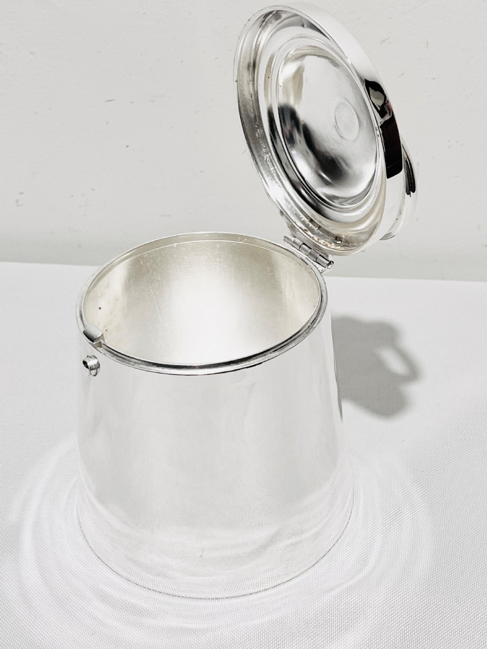 A polished silver plated cylindrical biscuit box designed in the form of a trade weight, featuring a fitted lid with a central ring handle. View VI