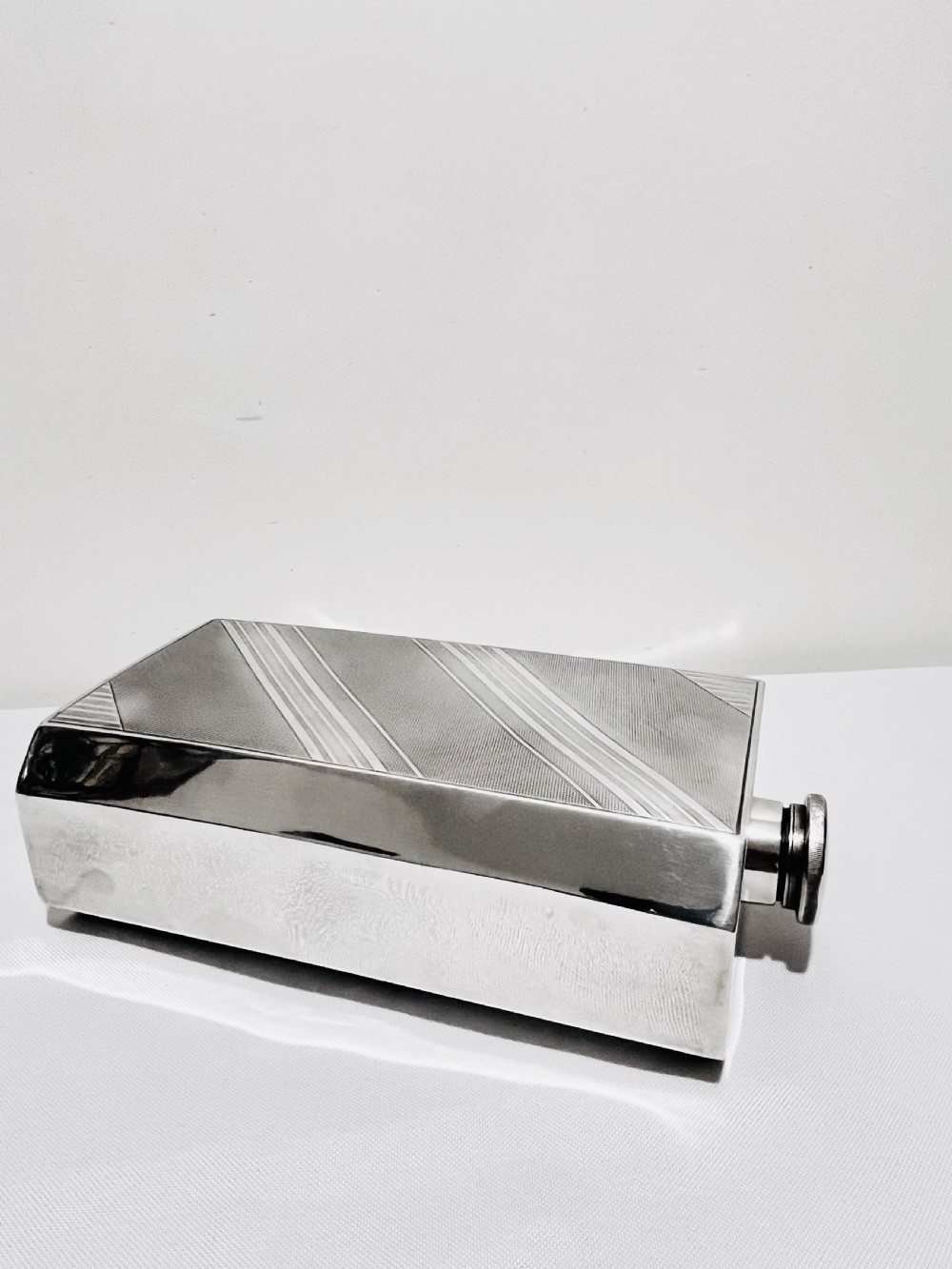 An Art Deco silver-plated giant spirit flask featuring geometric engine-turned pattern work and a cylindrical screw cap.