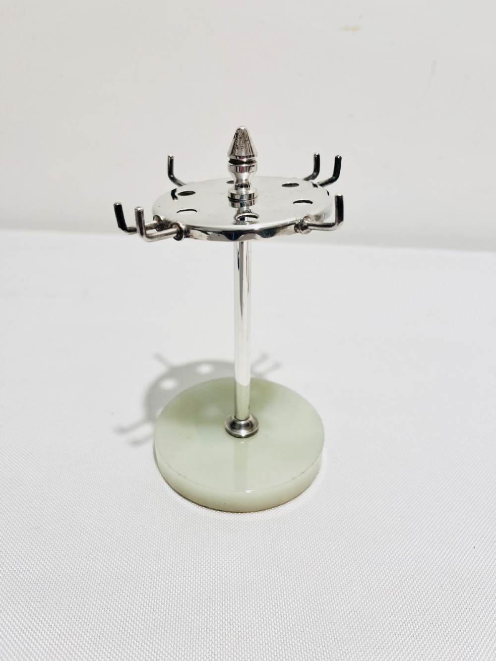 An Art Deco silver-plated bar set featuring miniature tankards, red-handled tools, and cherry cocktail picks arranged on a circular stand with a pale onyx base. View V