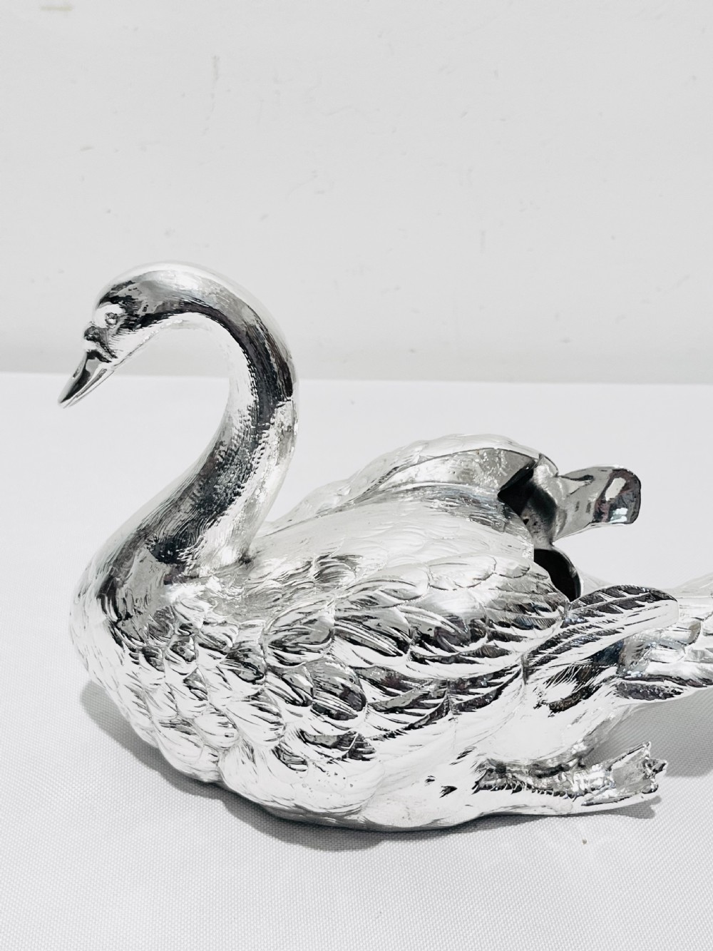 An antique silver-plated novelty spoon warmer cast in the detailed shape of a resting swan.