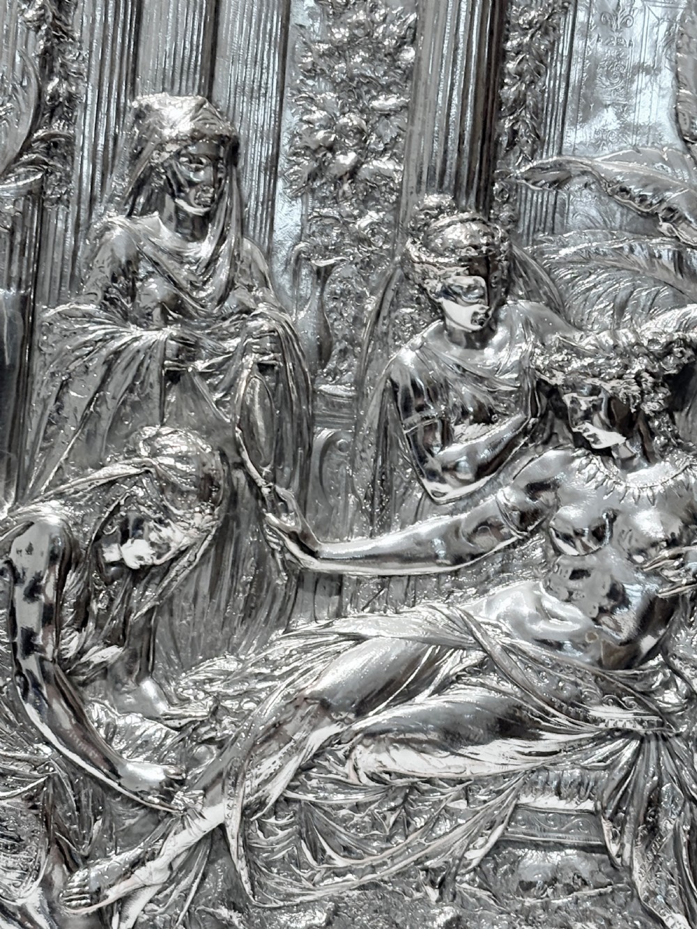 A circular silver plate electrotype charger featuring a detailed relief depiction of classical figures framed by ornate scrolled borders. View II