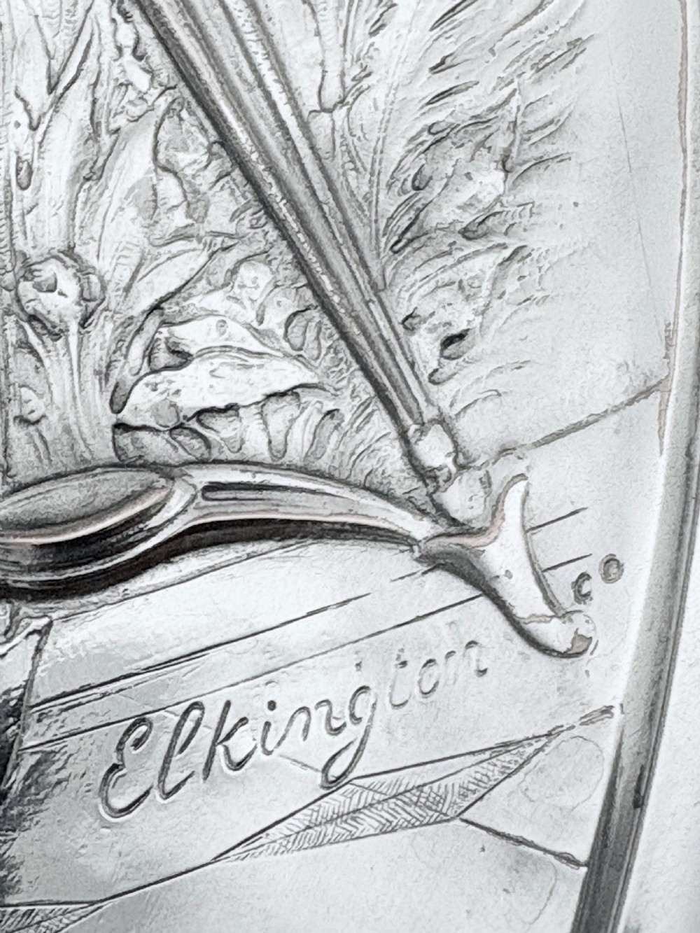 A circular silver plate electrotype charger featuring a detailed relief depiction of classical figures framed by ornate scrolled borders. View XIII
