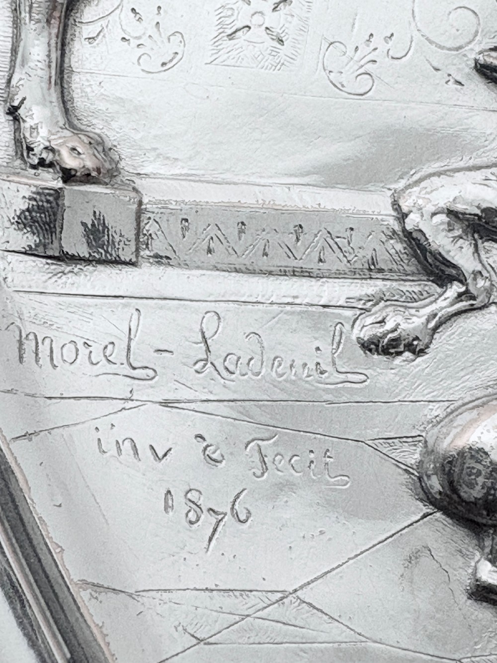 A circular silver plate electrotype charger featuring a detailed relief depiction of classical figures framed by ornate scrolled borders. View XIV