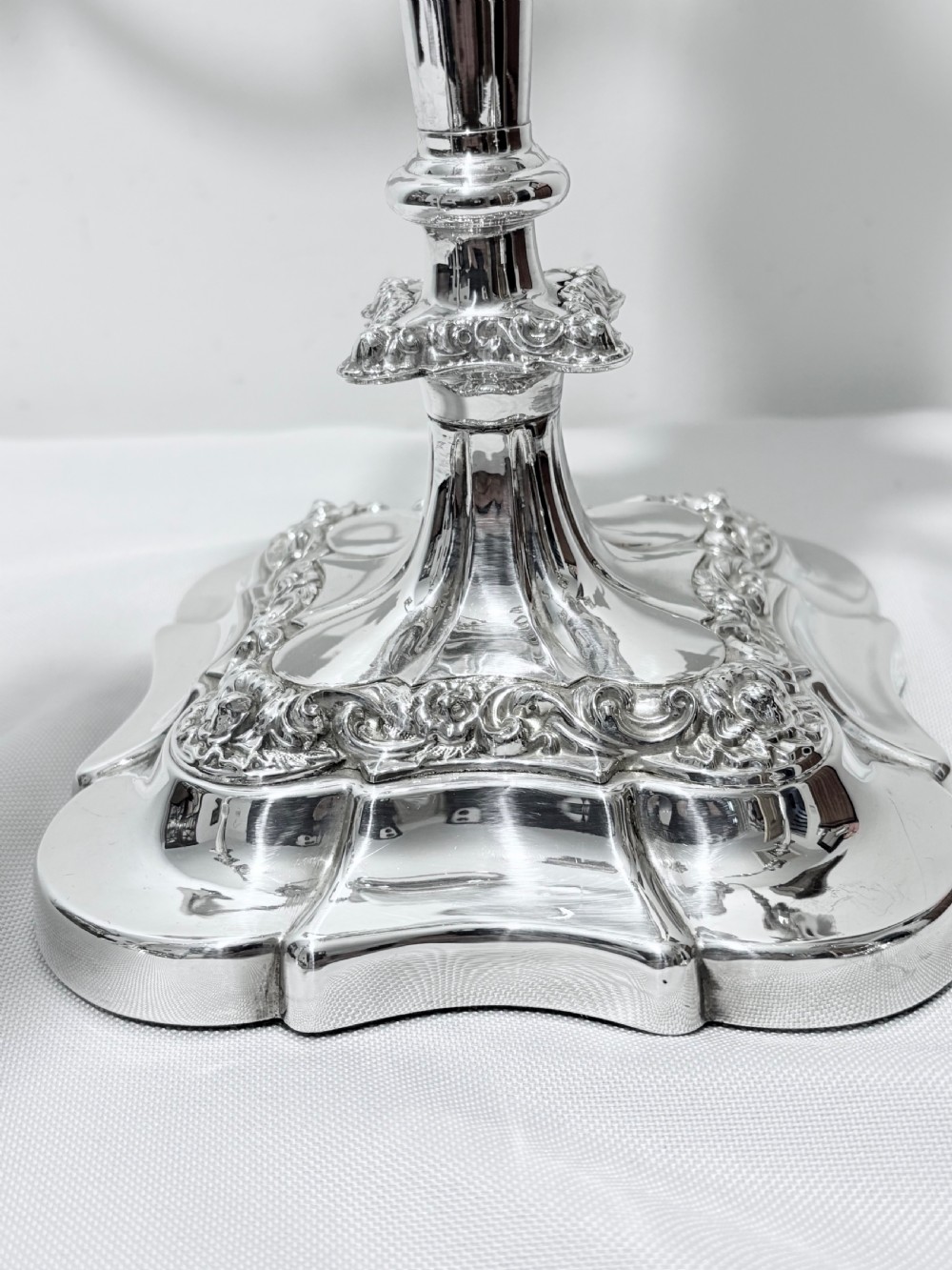 A three-piece antique silver-plated candelabra suite consisting of a central five-light branch candelabrum flanked by two matching single candlesticks. View II
