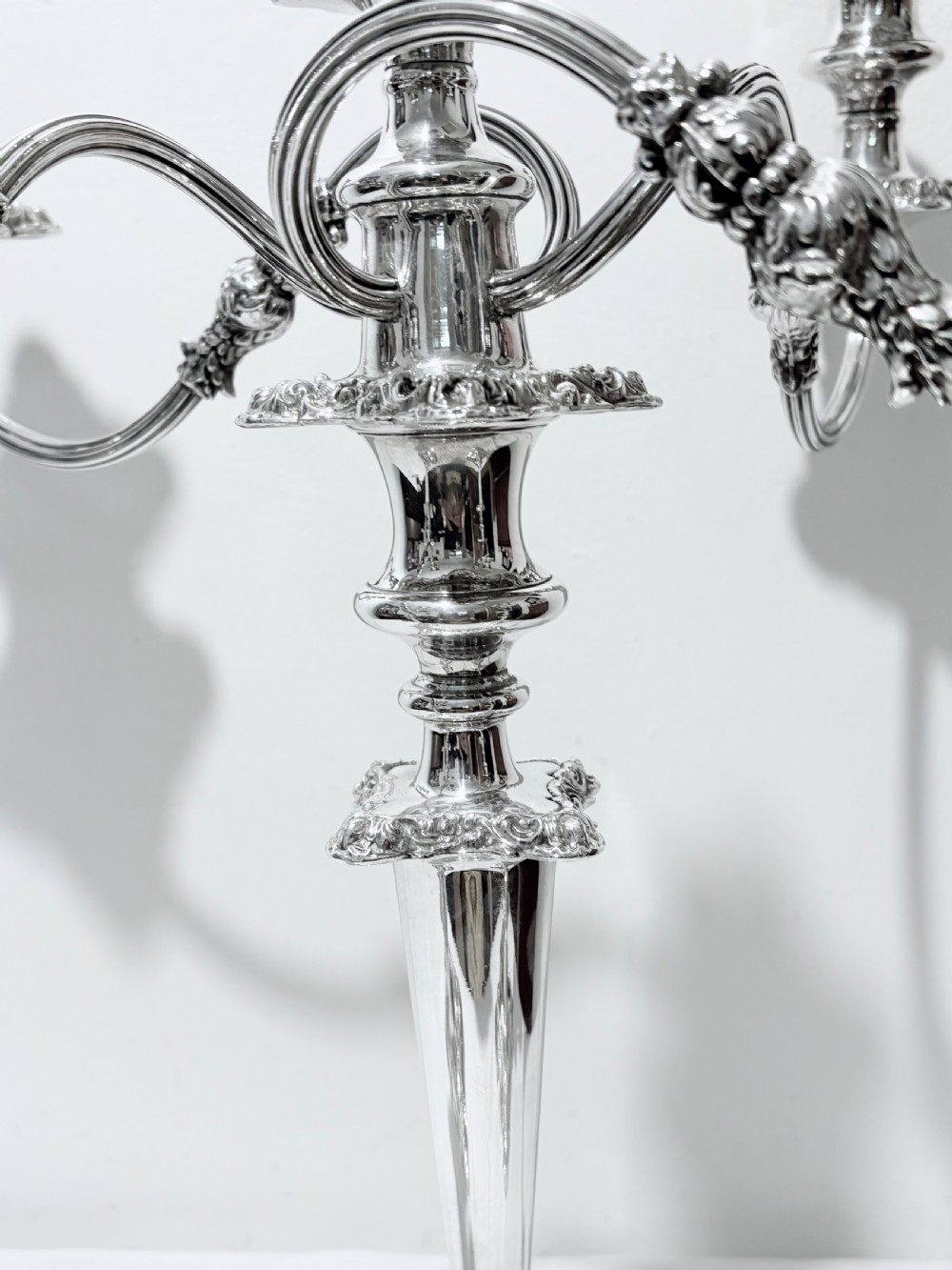 A three-piece antique silver-plated candelabra suite consisting of a central five-light branch candelabrum flanked by two matching single candlesticks. View III