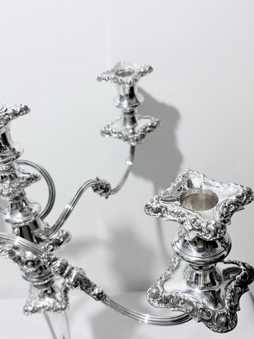 A three-piece antique silver-plated candelabra suite consisting of a central five-light branch candelabrum flanked by two matching single candlesticks. View IV