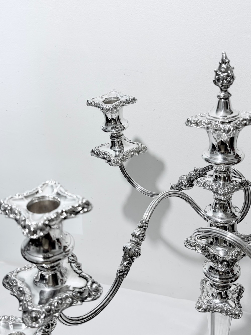 A three-piece antique silver-plated candelabra suite consisting of a central five-light branch candelabrum flanked by two matching single candlesticks. View V
