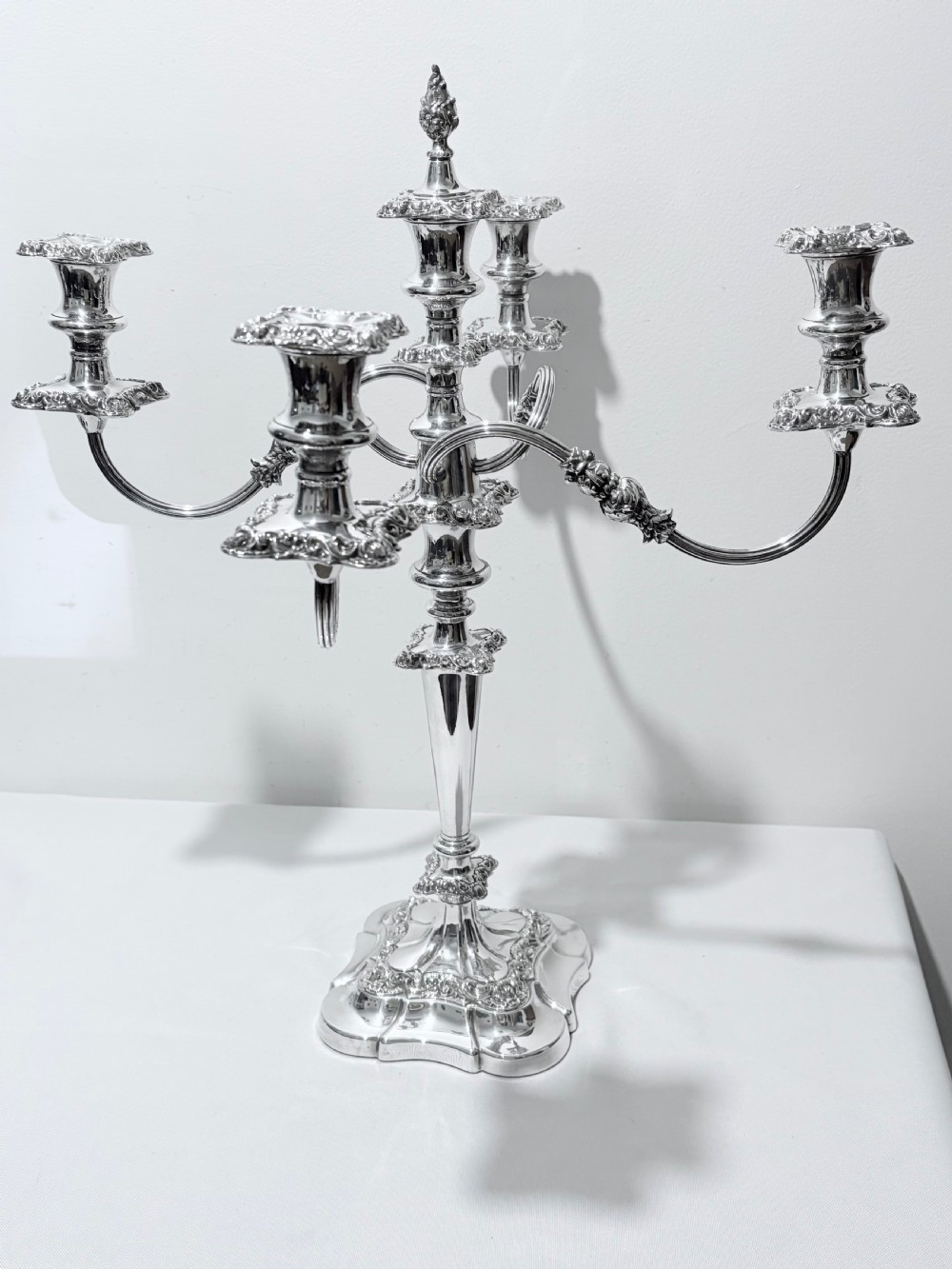 A three-piece antique silver-plated candelabra suite consisting of a central five-light branch candelabrum flanked by two matching single candlesticks. View IX