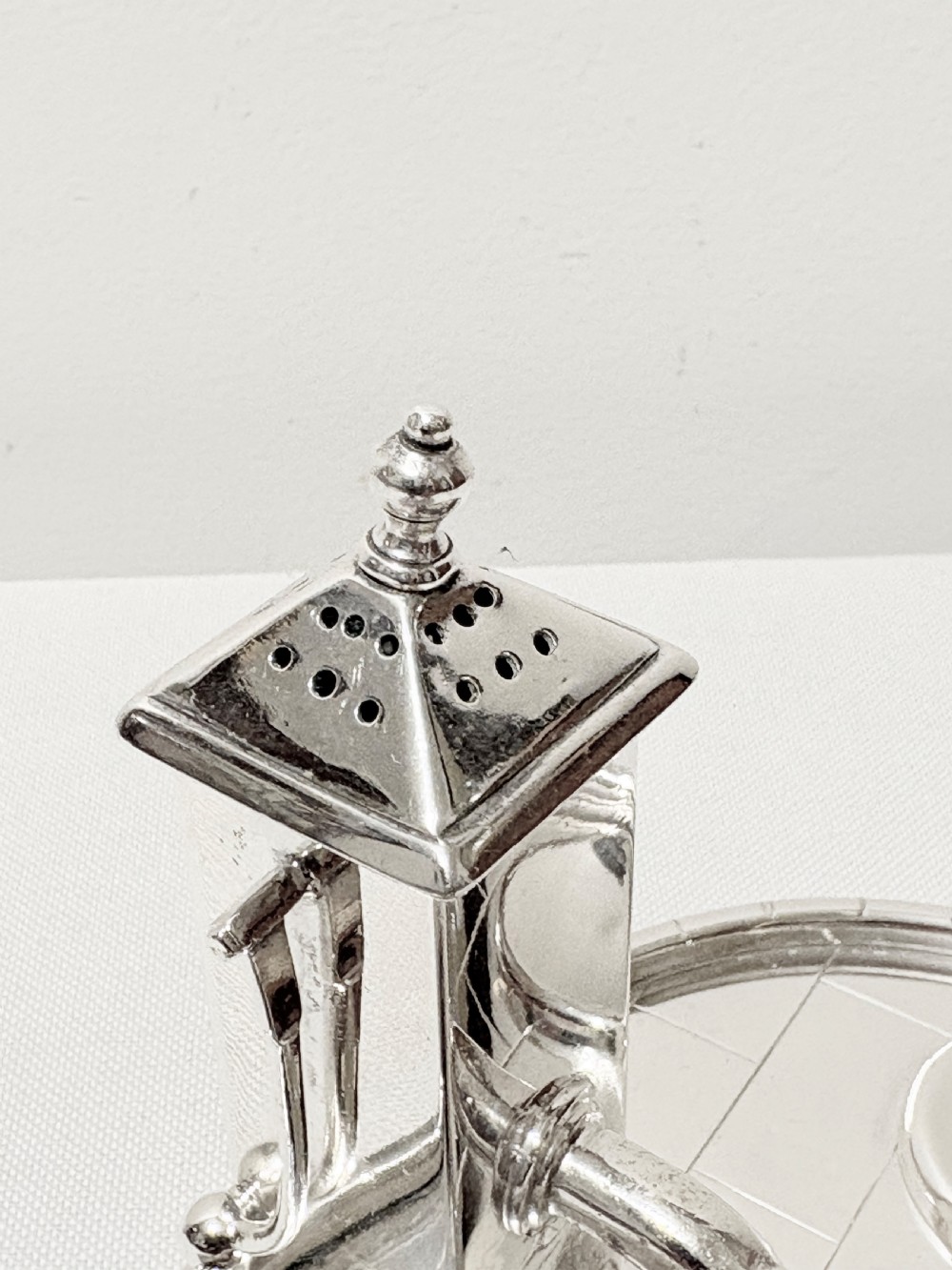 A Victorian silver-plated novelty cruet set featuring a central water pump pepper caster, a bucket salt cellar, and a milk churn mustard pot on a circular engraved tray. View III