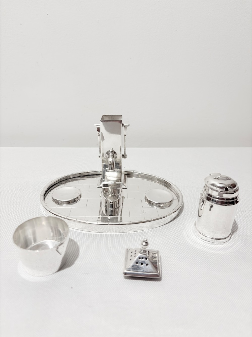 A Victorian silver-plated novelty cruet set featuring a central water pump pepper caster, a bucket salt cellar, and a milk churn mustard pot on a circular engraved tray. View IV