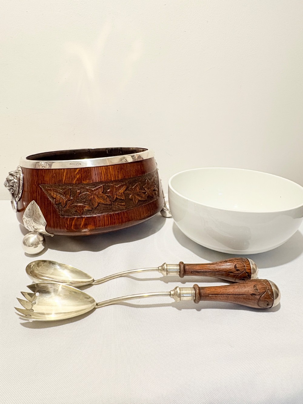 A late Victorian carved oak salad bowl with silver-plated rim, ball feet, and a white ceramic liner, featuring an ivy leaf carved band around the exterior. View VI