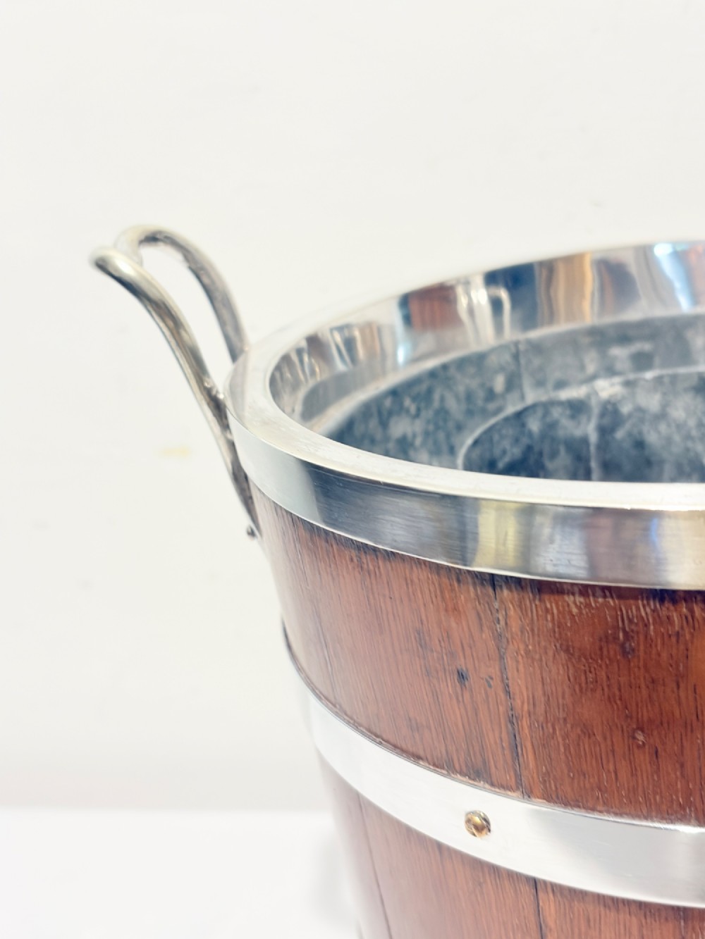 An antique coopered oak wine bucket featuring polished silver-plated bands, twin side handles, and a removable metal liner. View V