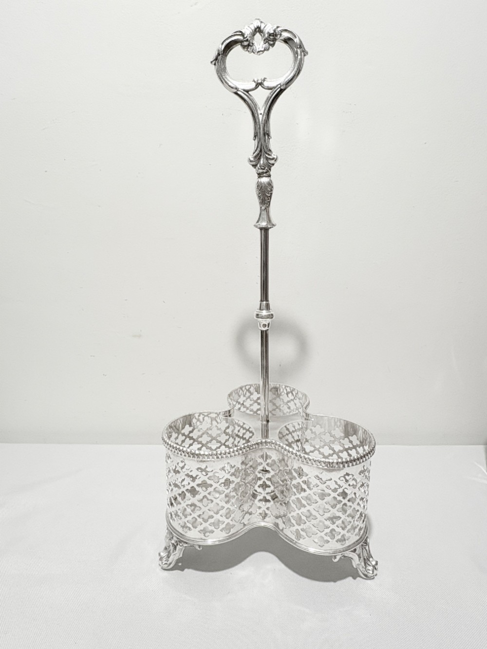 A Victorian silver-plated decanter stand holding three colourful cut-to-clear glass bottles in pink, blue, and deep red with faceted stoppers. View VI