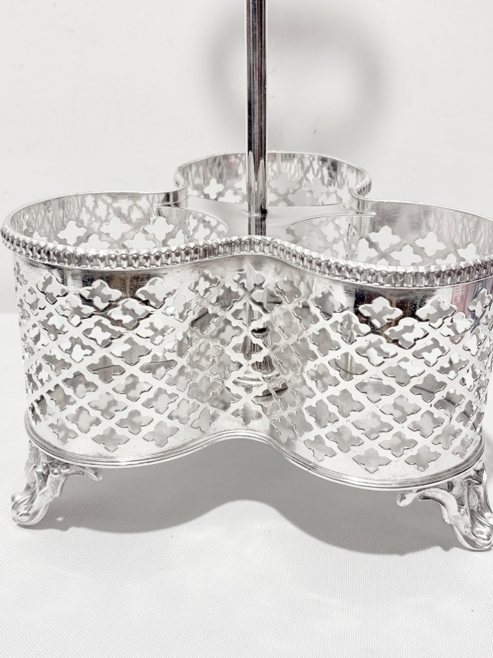 A Victorian silver-plated decanter stand holding three colourful cut-to-clear glass bottles in pink, blue, and deep red with faceted stoppers. View VII