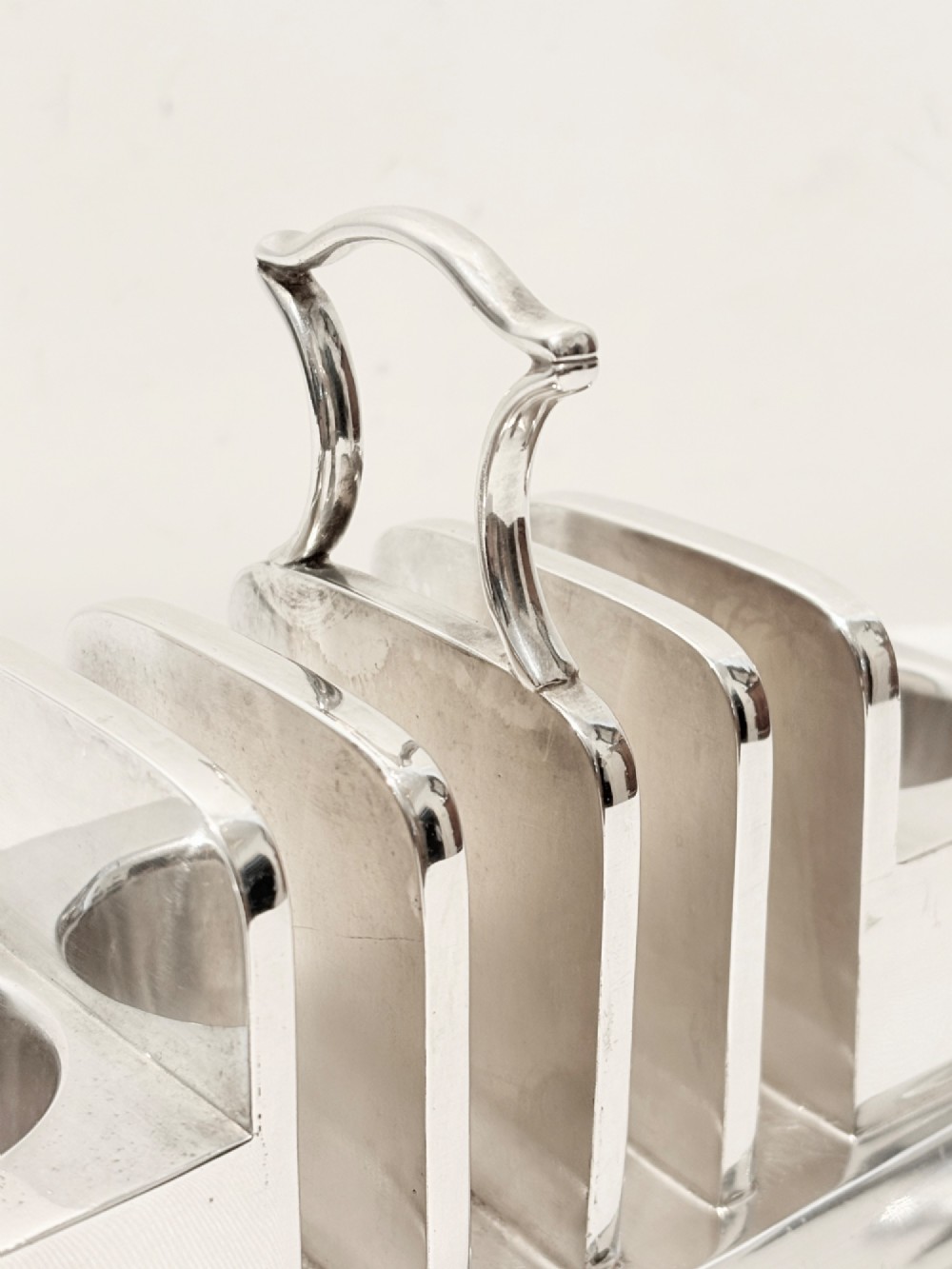 A Victorian silver-plated toast rack with radiator-style dividers flanked by two integrated egg holders on a rectangular base with ball feet. View III