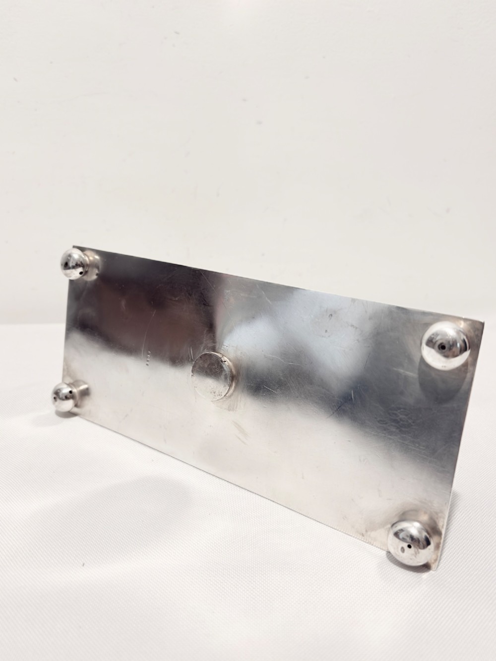 A Victorian silver-plated toast rack with radiator-style dividers flanked by two integrated egg holders on a rectangular base with ball feet. View V