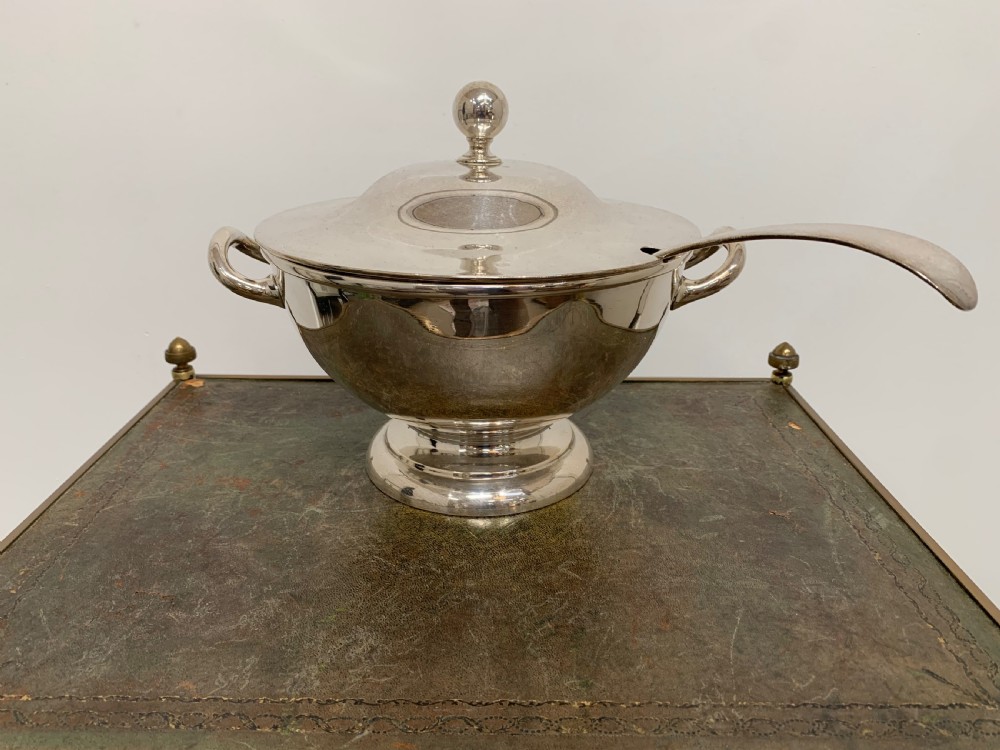 A Victorian silver-plated two-handled soup tureen featuring a domed lid, spherical finial, matching ladle, and pedestal base.
