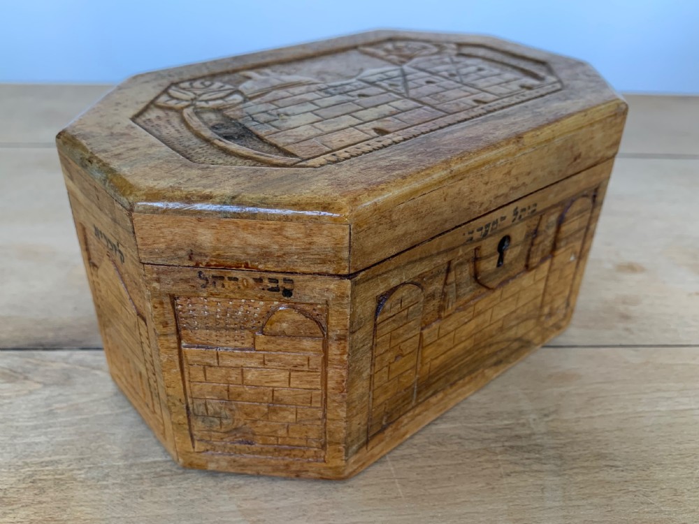 An octagonal carved olivewood Etrog box decorated with relief carvings of Jerusalem architecture and Hebrew lettering above a keyhole. View II
