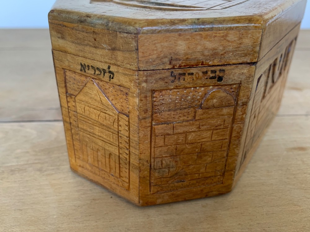 An octagonal carved olivewood Etrog box decorated with relief carvings of Jerusalem architecture and Hebrew lettering above a keyhole. View VI