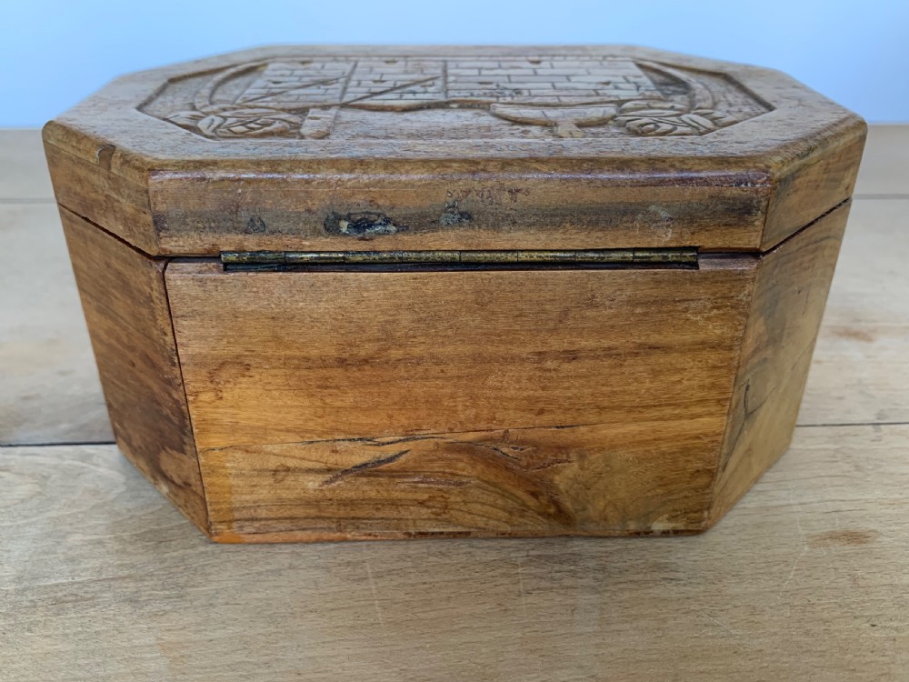 An octagonal carved olivewood Etrog box decorated with relief carvings of Jerusalem architecture and Hebrew lettering above a keyhole. View VII