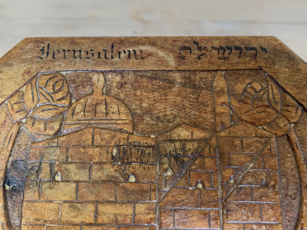 An octagonal carved olivewood Etrog box decorated with relief carvings of Jerusalem architecture and Hebrew lettering above a keyhole. View XI