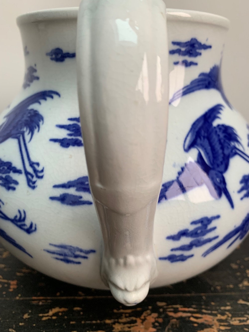A bulbous white ceramic jug featuring transfer-printed blue flying cranes, a crackle glaze finish, and a moulded handle. View III
