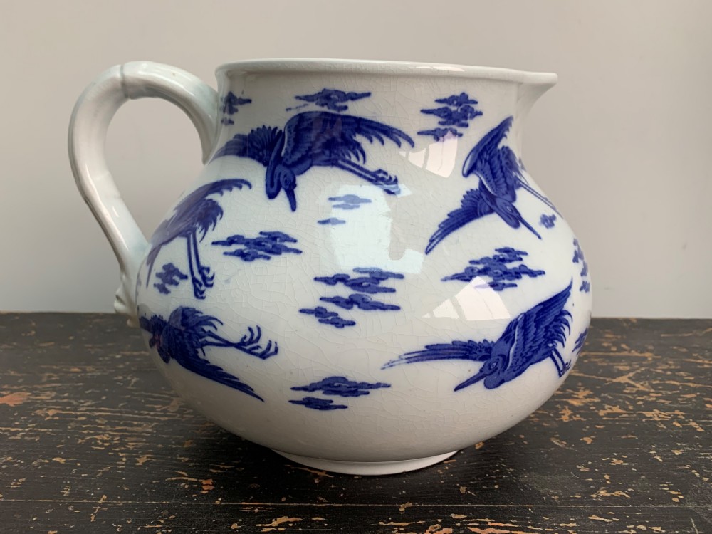 A bulbous white ceramic jug featuring transfer-printed blue flying cranes, a crackle glaze finish, and a moulded handle. View IV