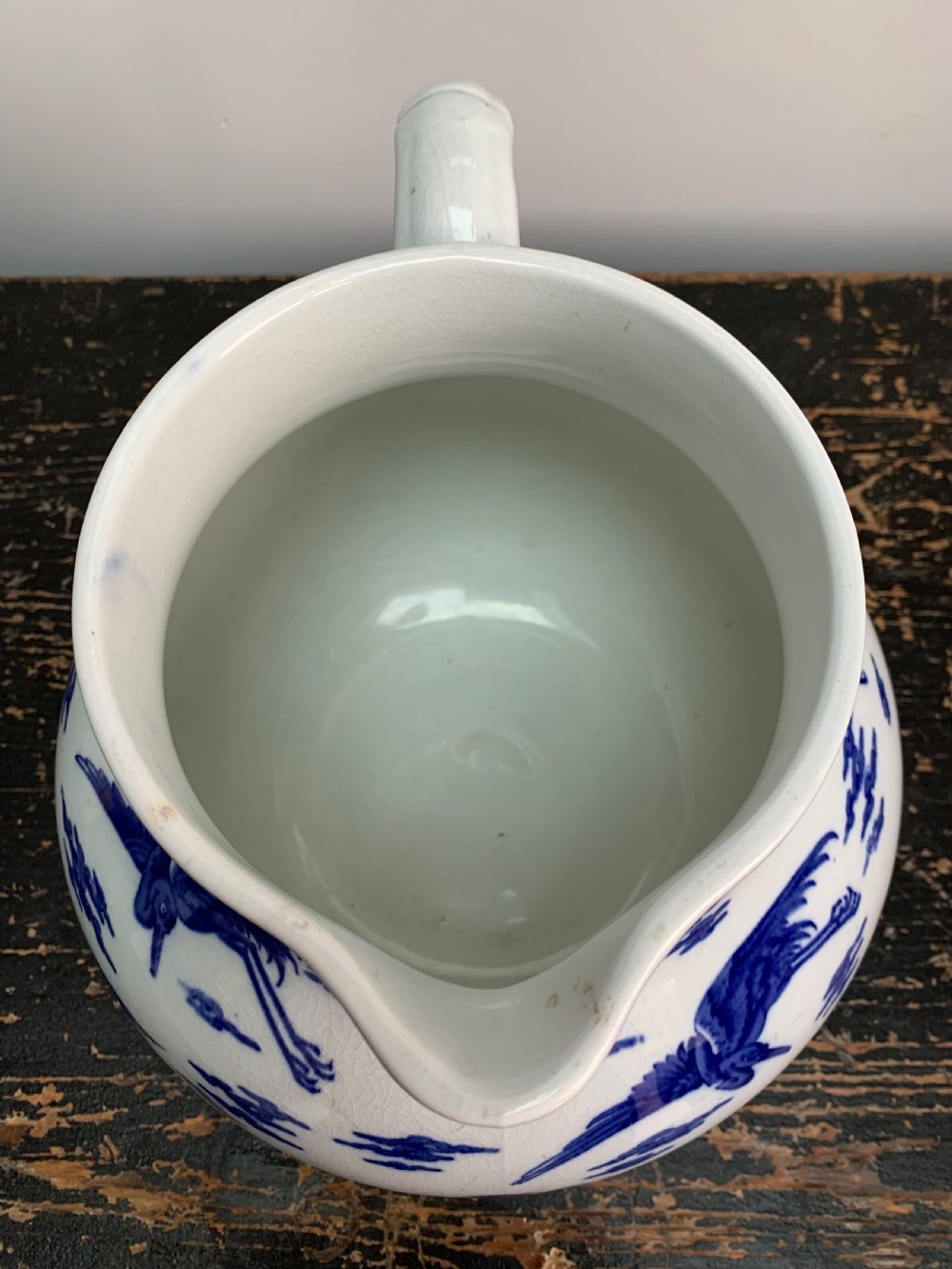 A bulbous white ceramic jug featuring transfer-printed blue flying cranes, a crackle glaze finish, and a moulded handle. View VIII
