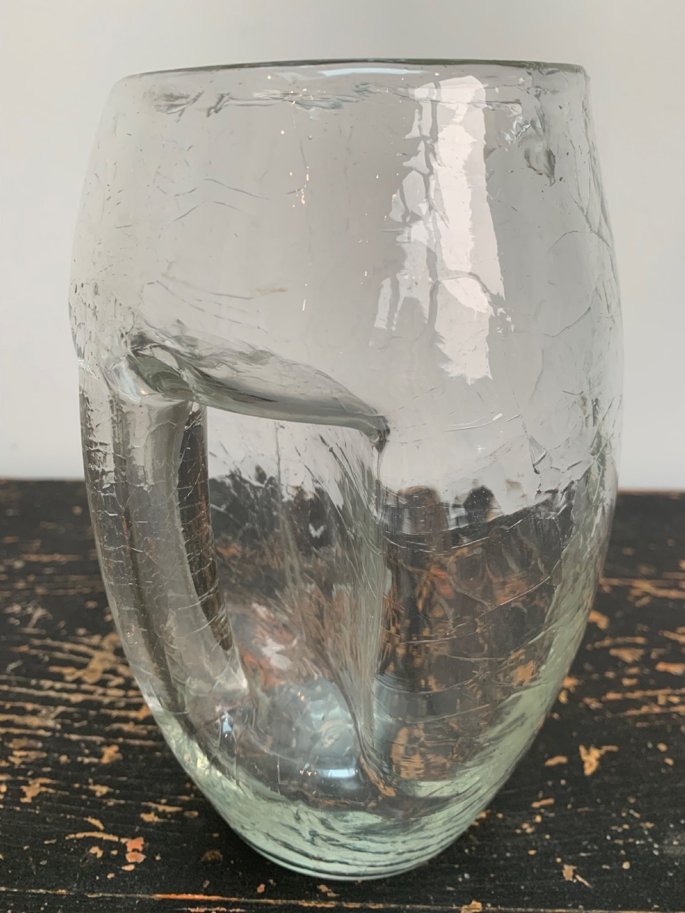 A clear blown glass jug featuring an all-over crackle finish and an integrated vertical handle. View IV