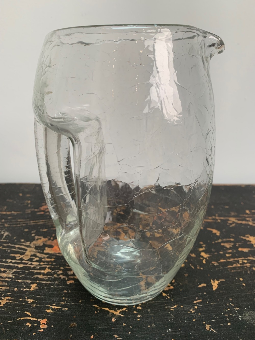 A clear blown glass jug featuring an all-over crackle finish and an integrated vertical handle. View V