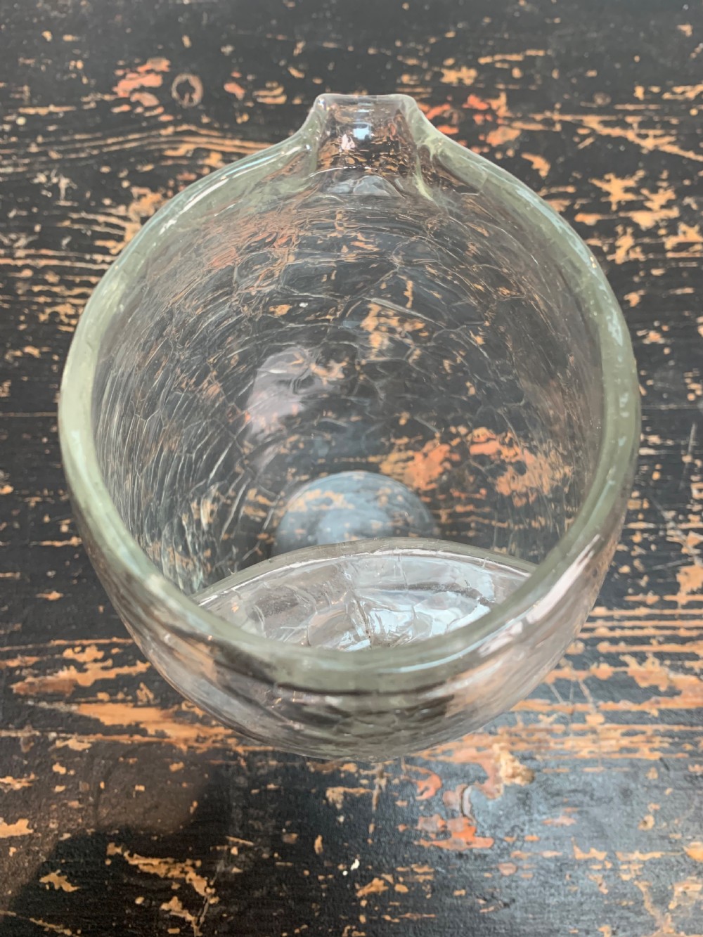 A clear blown glass jug featuring an all-over crackle finish and an integrated vertical handle. View VII