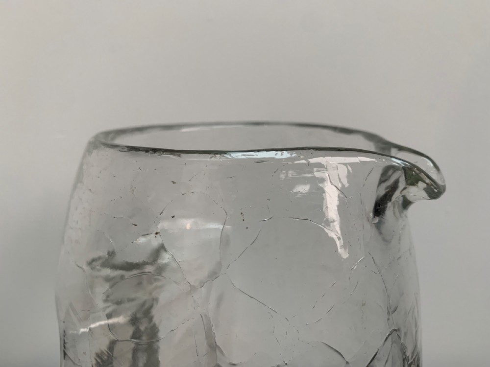 A clear blown glass jug featuring an all-over crackle finish and an integrated vertical handle. View VIII