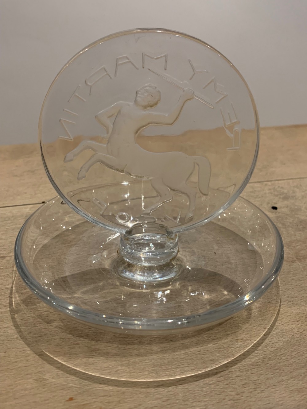 A clear glass Art Deco circular ashtray featuring an upright circular medallion with a frosted relief depicting a centaur holding a javelin above the lettering REMY MARTIN V.S.O.P. View V