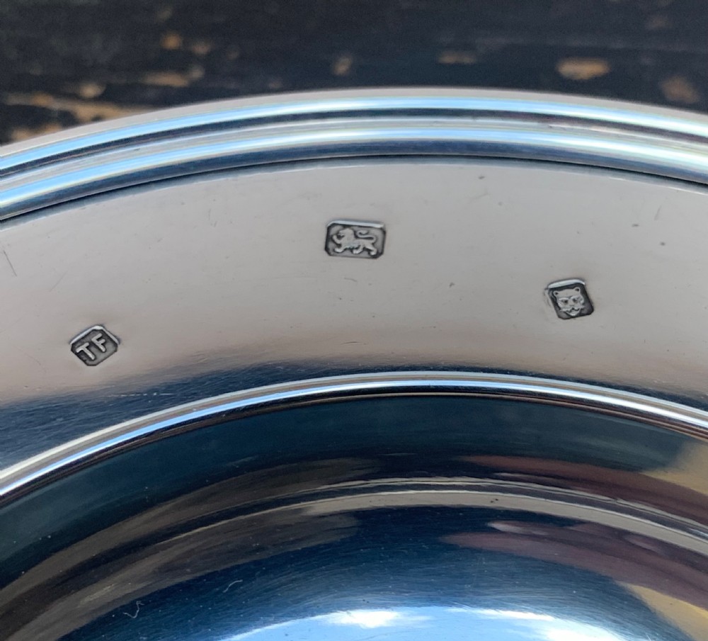 A circular solid silver ashtray featuring a realistic silver trompe loeil cigar resting across its moulded rim. View III