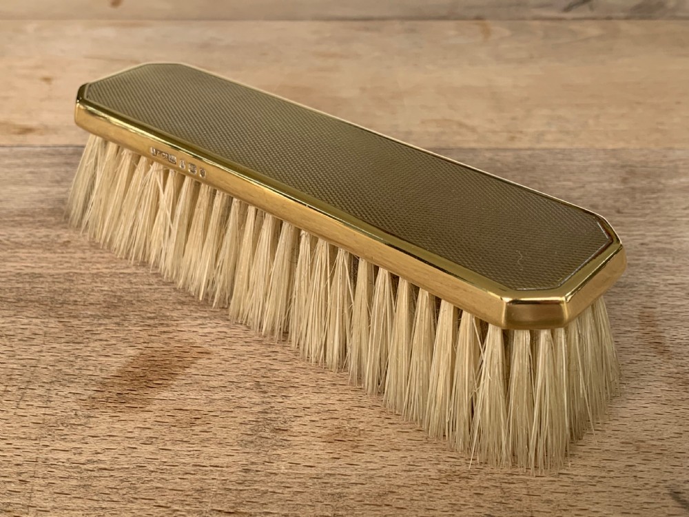 An Art Deco engine-turned silver-gilt rectangular clothes brush by Asprey with dense light-coloured natural bristles.