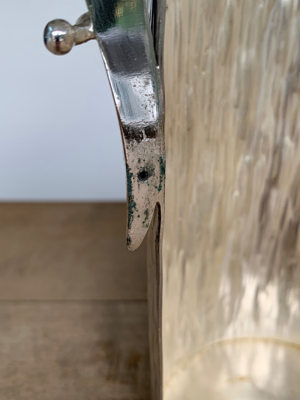 A 19th-century silver-plated wine bottle holder featuring a textured bark effect finish and a long sweeping curved handle. View X